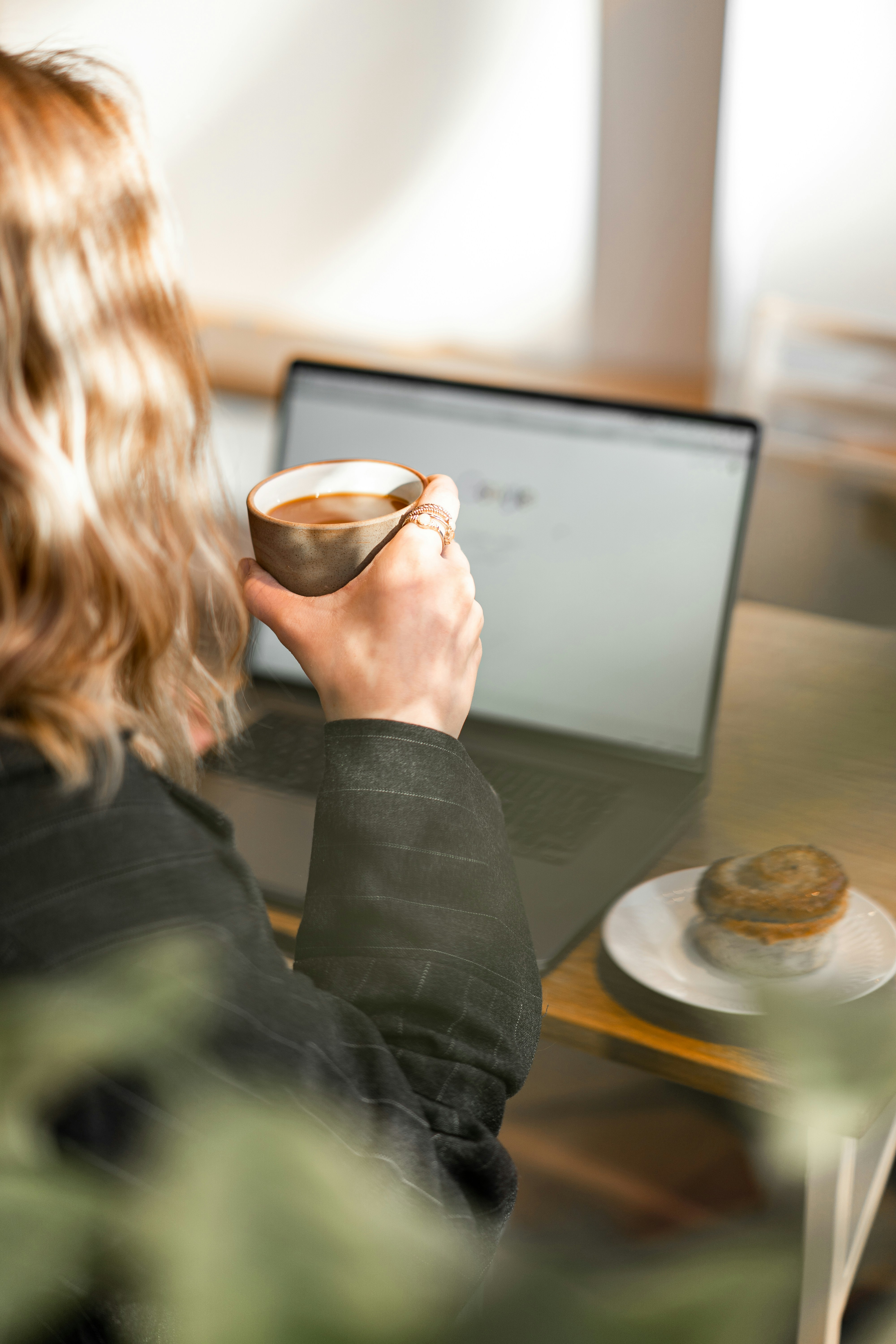 Business owner researching GovWin IQ alternatives on a laptop over morning coffee